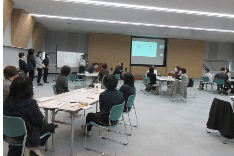 広島県三次市で開催された8050問題に関する合同研修会。グループワークで検討した内容を代表者が発表し、参加者が発表を聞いている様子。