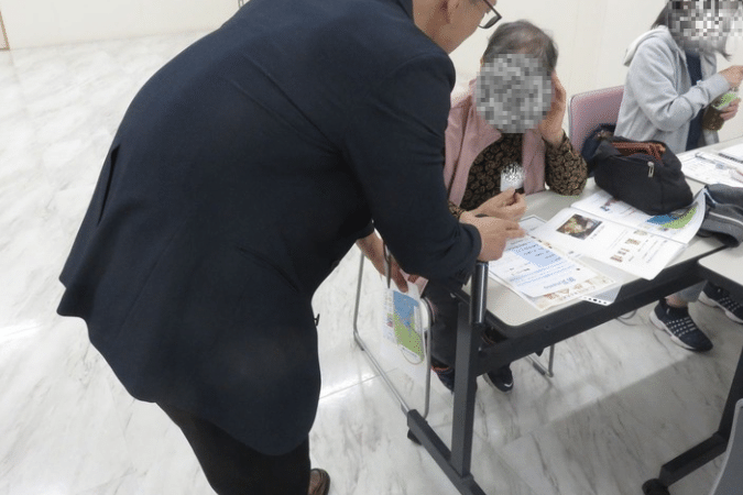 芝地区防災講座で、参加者に防災メモを作成してもらい、防災士の講師が一人ひとりに声をかけながら、災害時に役立つ情報の整理や日頃からの備えについて説明している様子。